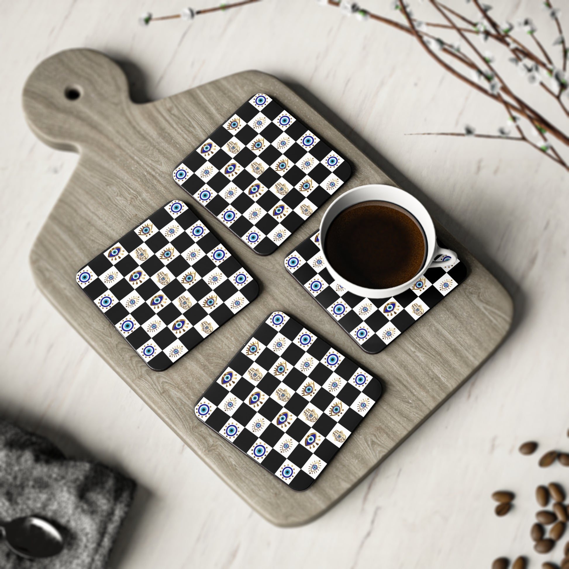 Set of four coasters with a evil eye design on a wooden cutting board with a cup of coffee.
