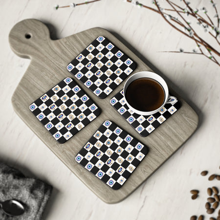 Set of four coasters with a evil eye design on a wooden cutting board with a cup of coffee.