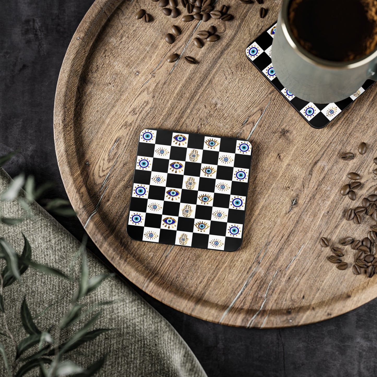 Checkered coaster with decorative patterns on a wooden tray with coffee and seeds.
