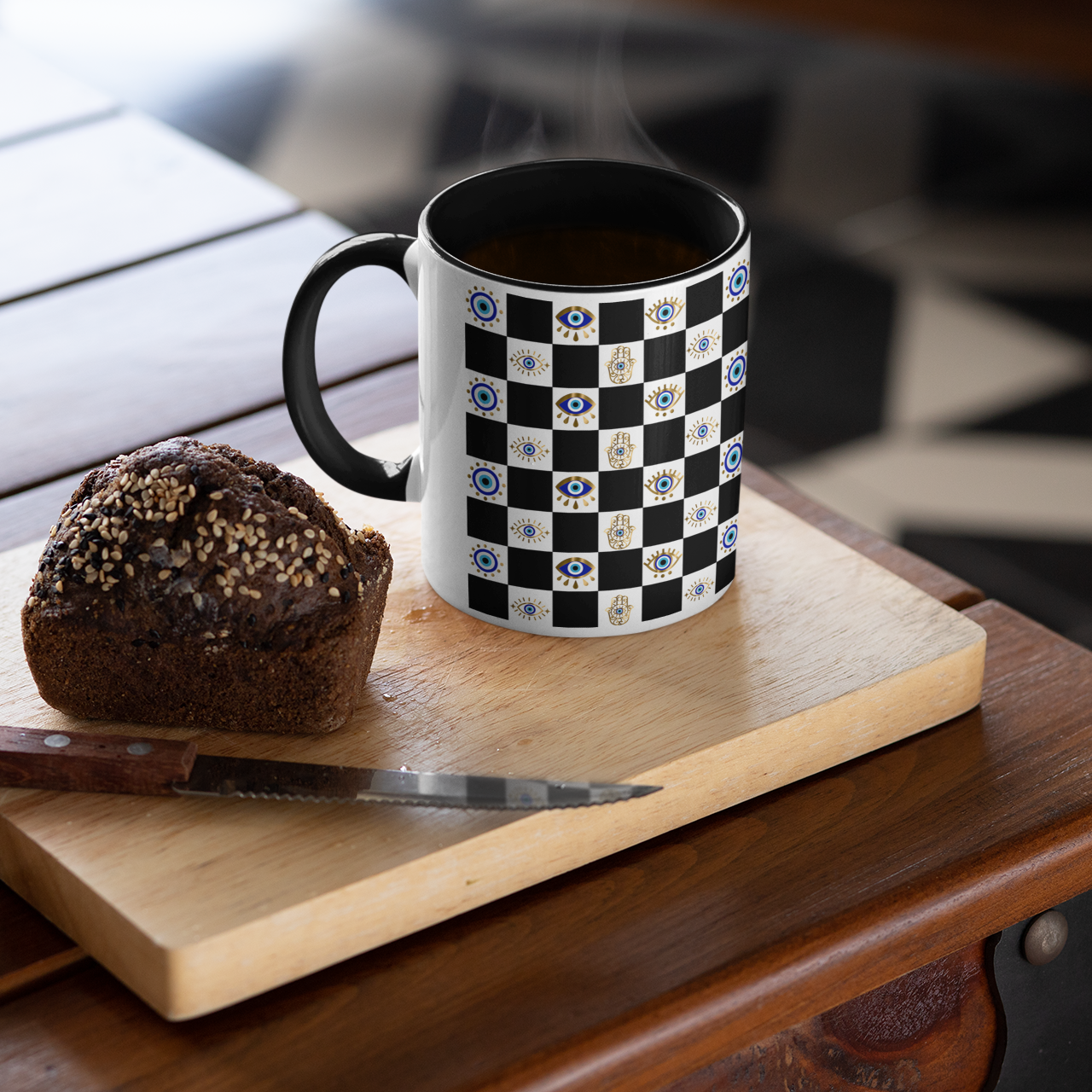 Black and white checkered mug with floral patterns on a wooden cutting board with a muffin.
