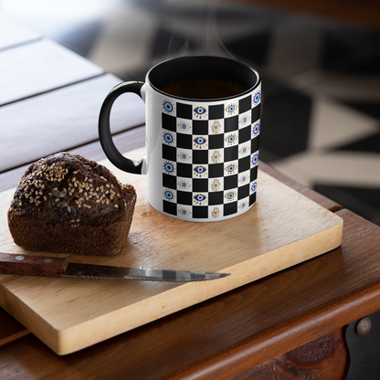 Black and white checkered mug with floral patterns on a wooden cutting board with a muffin.