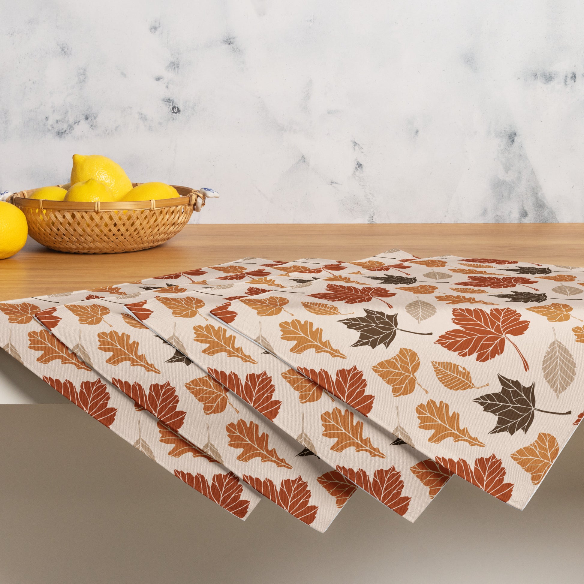 Set of fall-themed paper napkins on a marble surface with lemons.