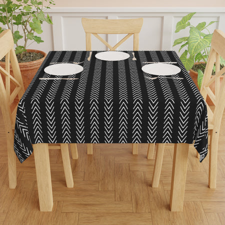 A black and mudcloth tablecloth with a geometric pattern laid out on a rectangular dining table.