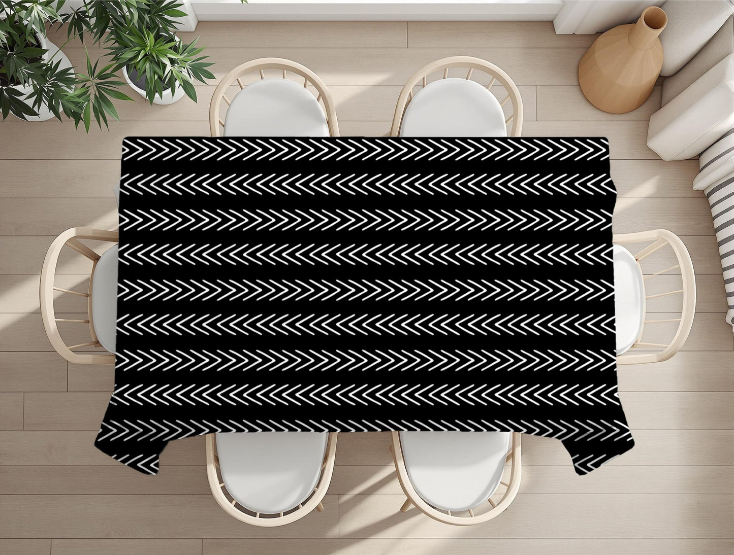 Black and white geometric patterned tablecloth on a dining table with chairs and plants in the background.