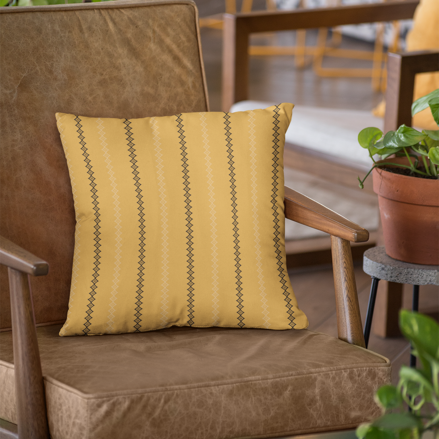 Yellow striped pillow on a brown chair with a blurred indoor setting
