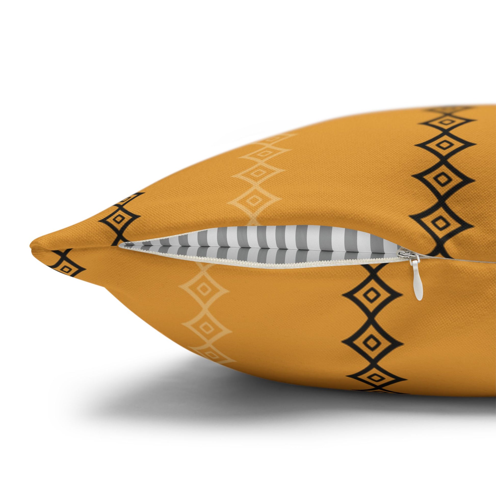 A gold mudcloth print throw pillow with black geometric patterns on a gray sofa.
