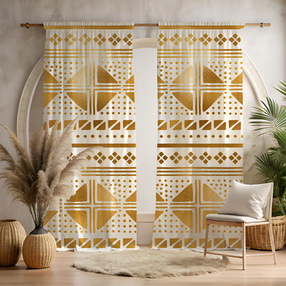 A pair of golden mudcloth dots window curtains with a geometric pattern, hanging in a room with a chair, wicker table, and decorative items.