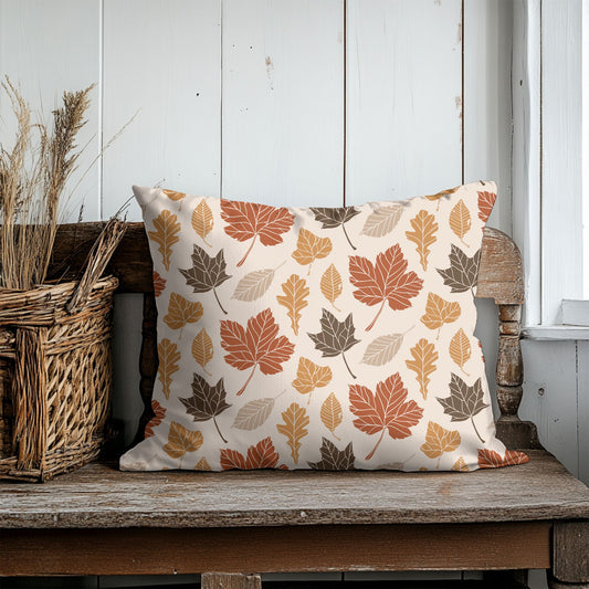 Decorative pillow with leaf pattern on a wooden bench against a white paneled wall.