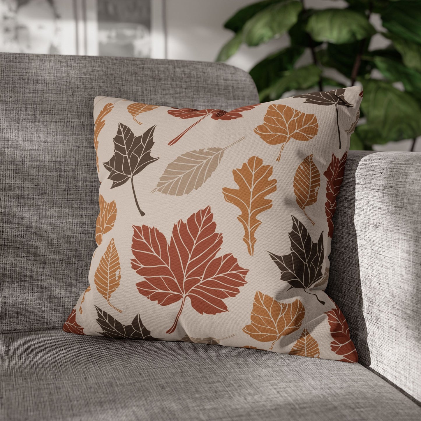 Decorative pillow with autumn leaf pattern on a gray sofa