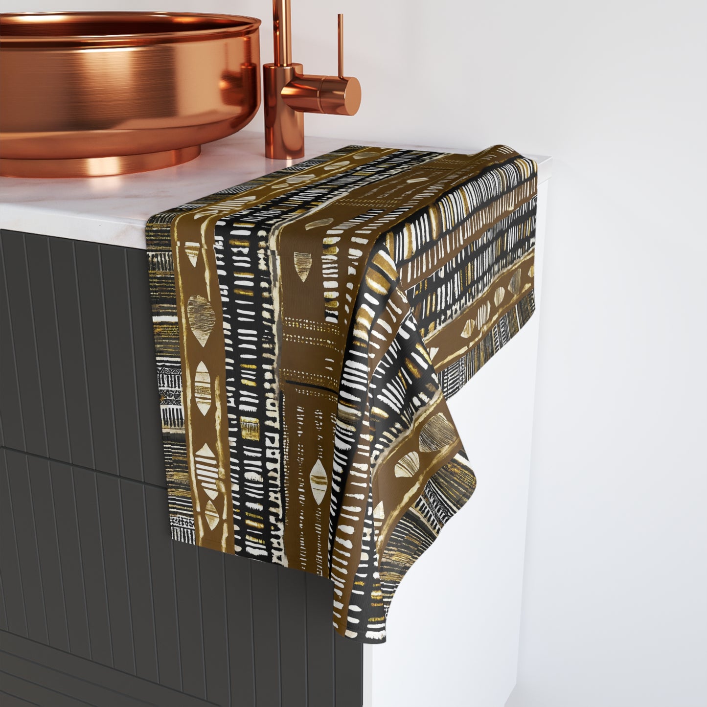 Patterned towel draped over a bathtub with copper fixtures.