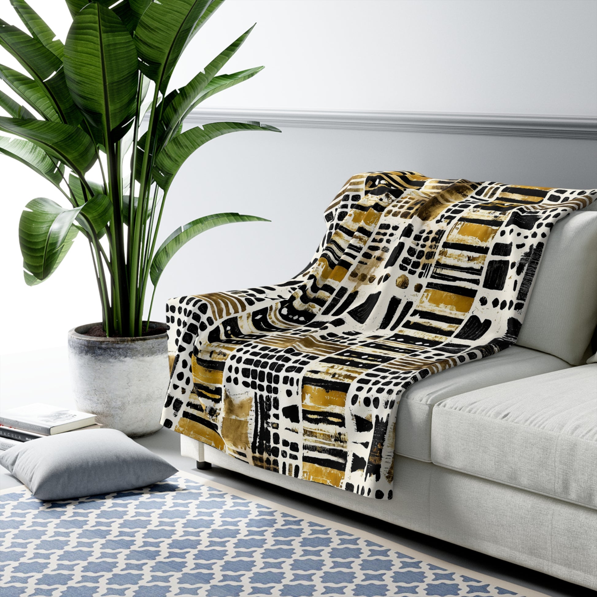 Patterned blanket draped over a sofa in a living room with a plant and rug.