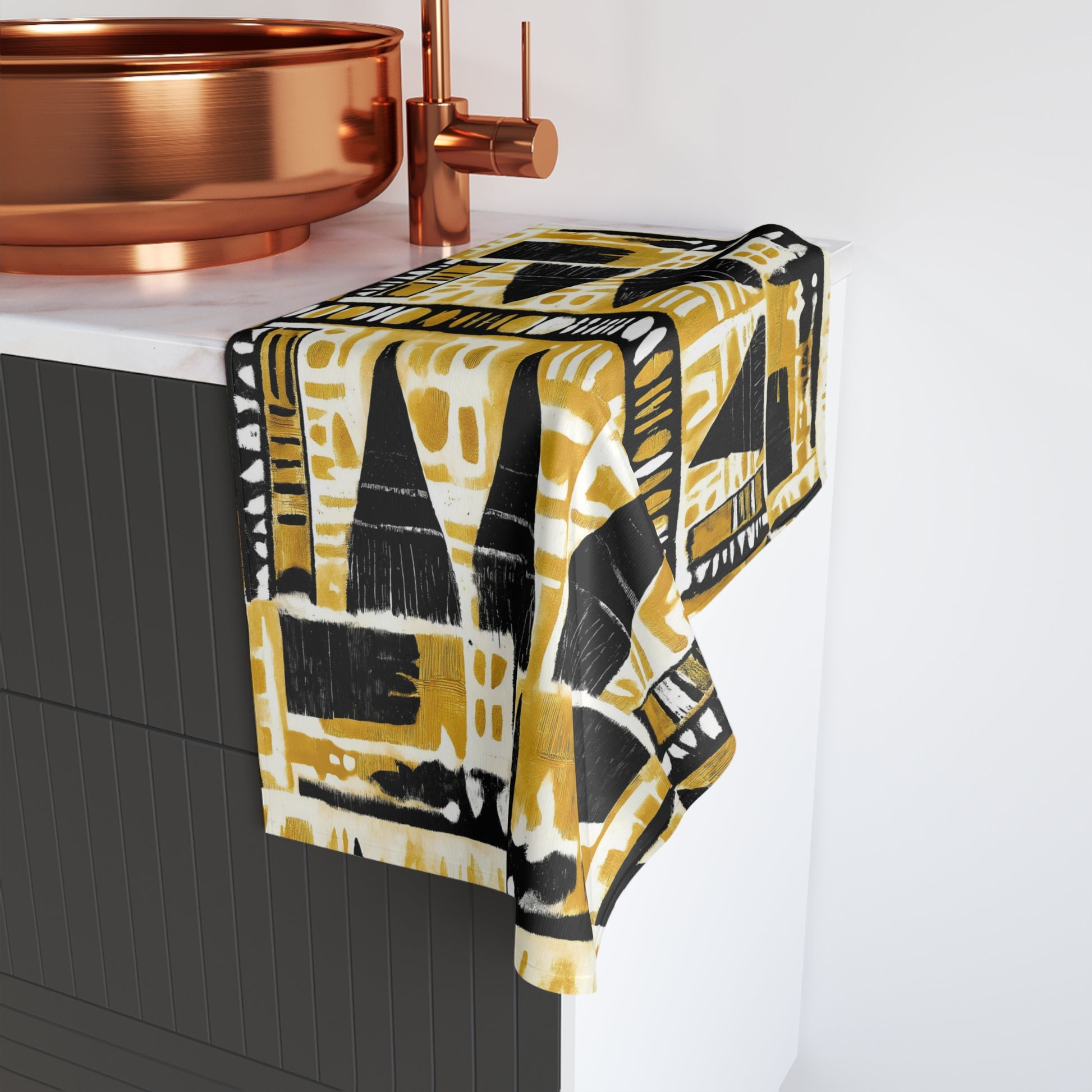 Yellow and black patterned towel hanging on a copper towel rack above a sink.