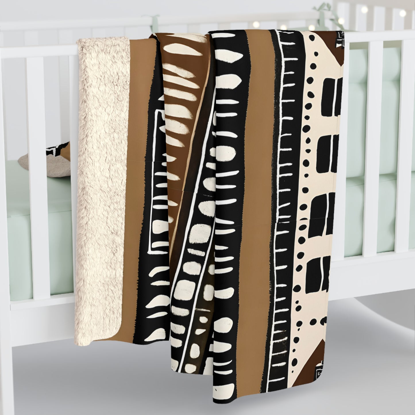 African blanket with abstract patterns draped over a white crib.