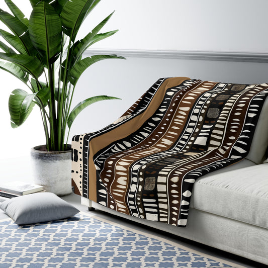 Mudcloth Patterned blanket draped over a sofa in a living room with a plant and rug.