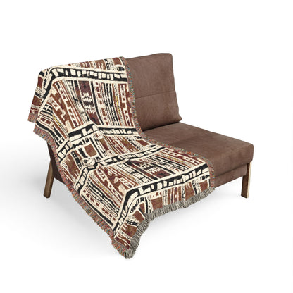 Bogolan patterned throw blanket draped over a brown chair on a white background