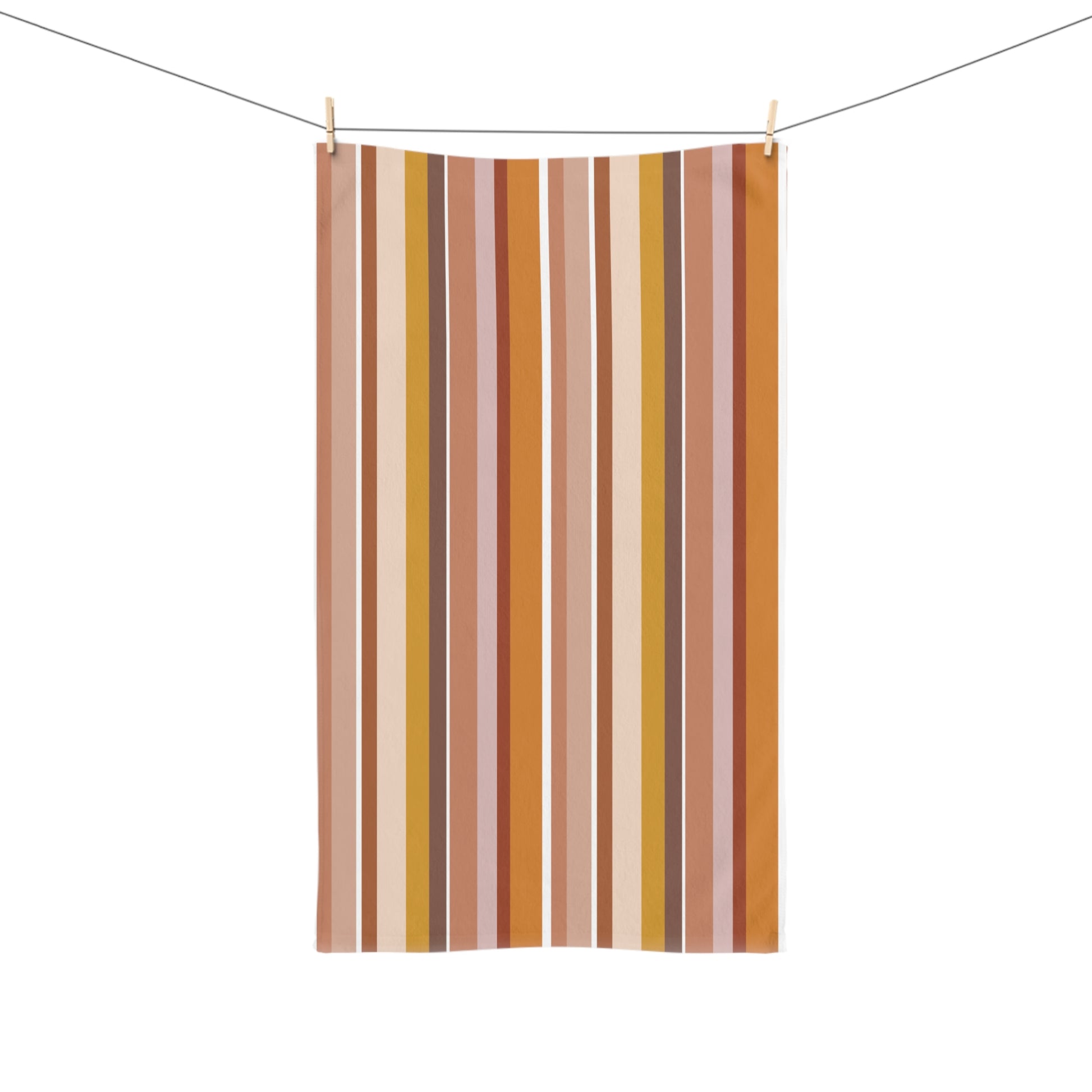 Striped towel with vertical brown, yellow, and pink stripes hanging on a line.