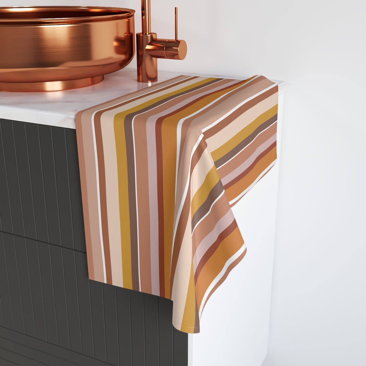 Pastel striped towel draped over a kitchen sink with copper fixtures.