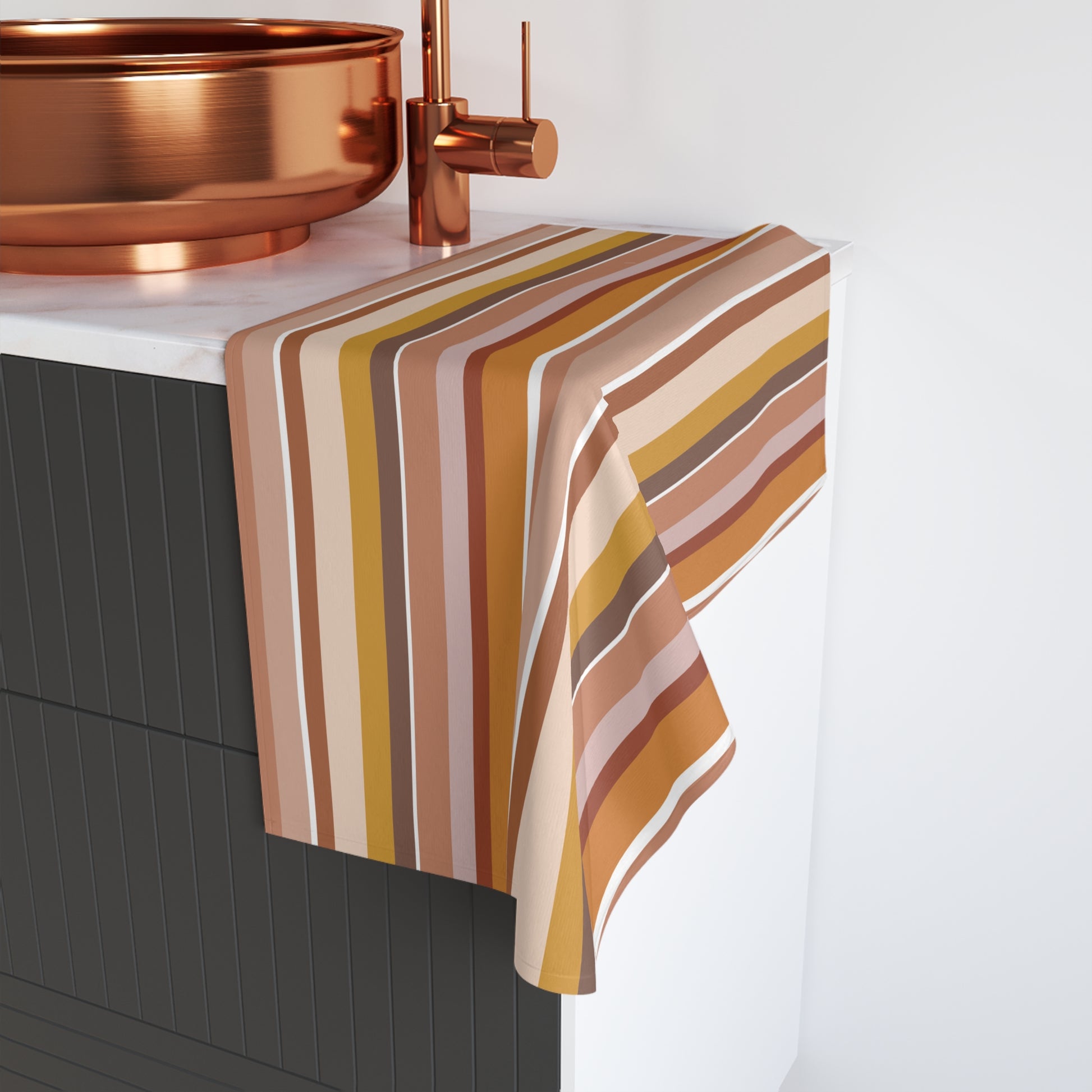 Pastel striped towel draped over a kitchen sink with copper fixtures.