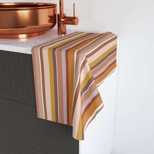 Pastel striped towel draped over a kitchen sink with copper fixtures.