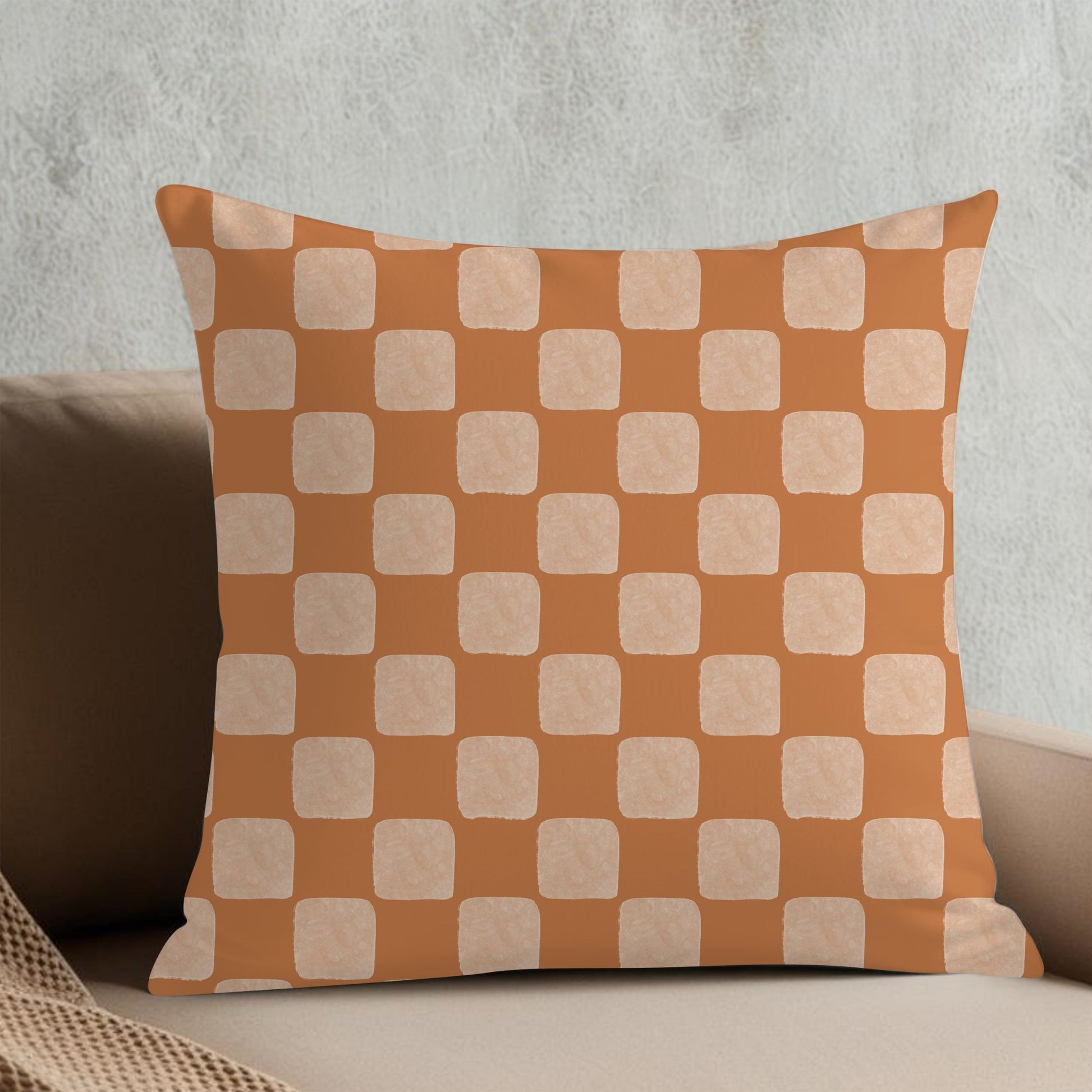 Checkered pillow with orange and beige pattern on a neutral background