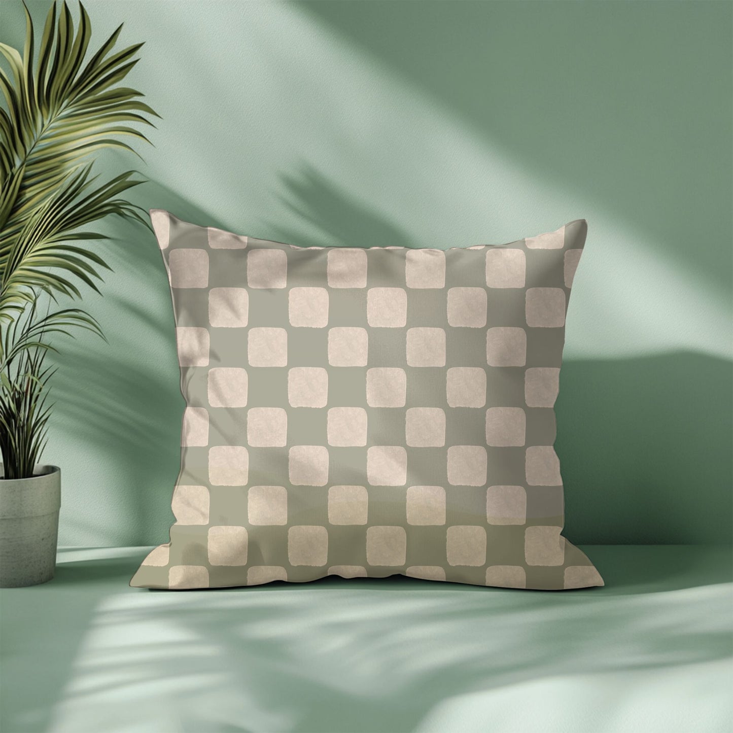 Checkered pillow on a light green background with a plant to the left