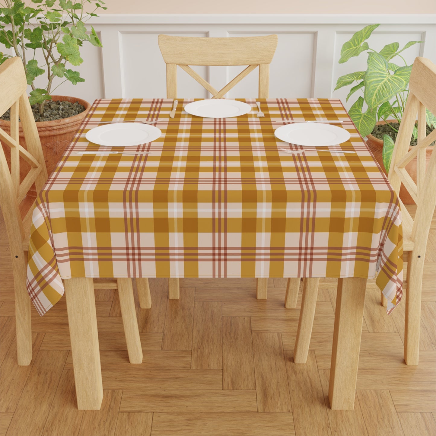 Dining table with a yellow checkered tablecloth, white plates, and wooden chairs on a wooden floor.