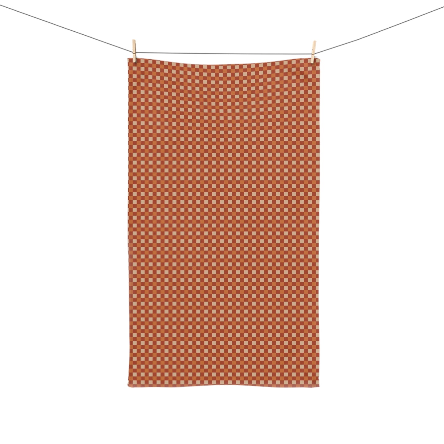 Orange checkered towel hanging on a line against a white background
