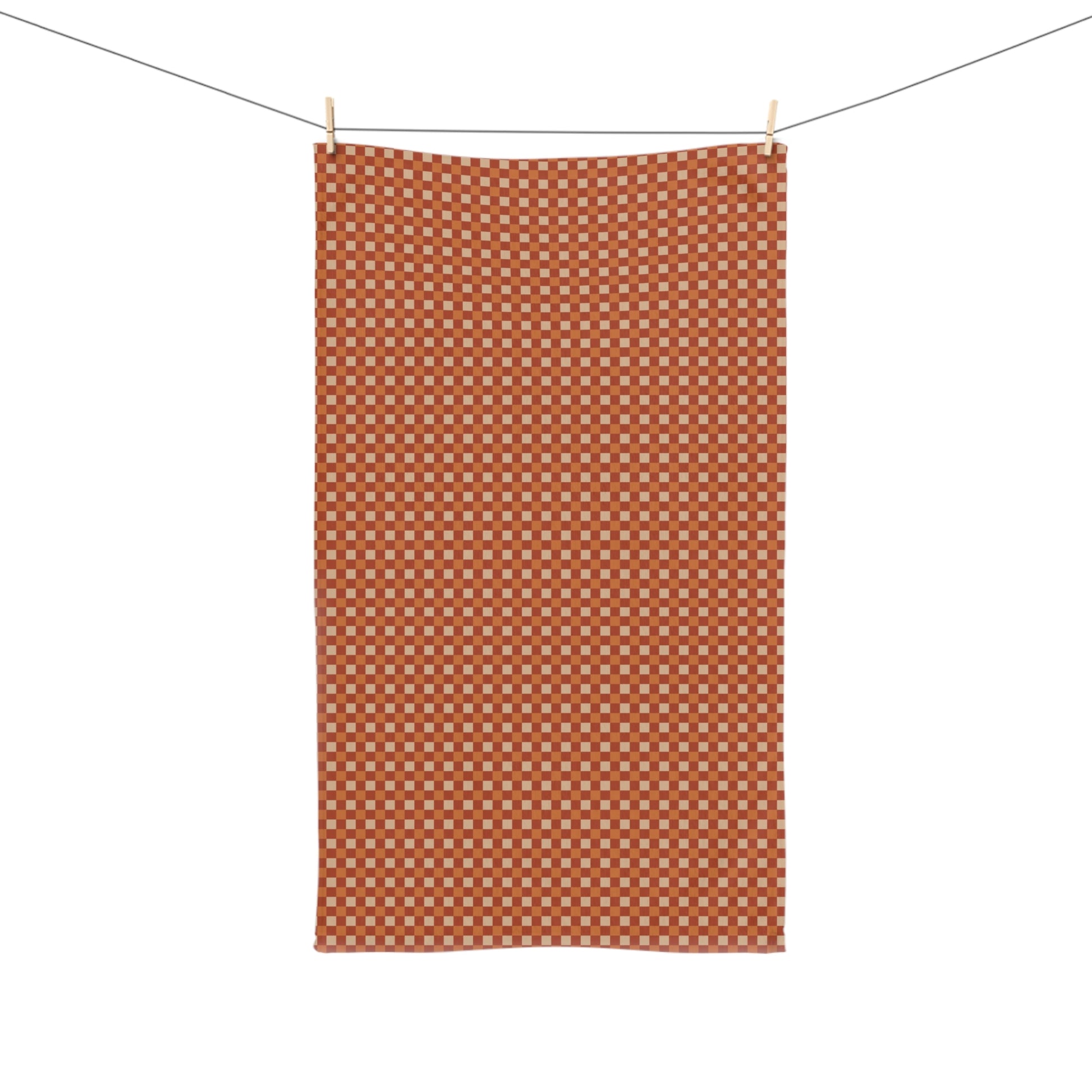 Orange checkered towel hanging on a line against a white background
