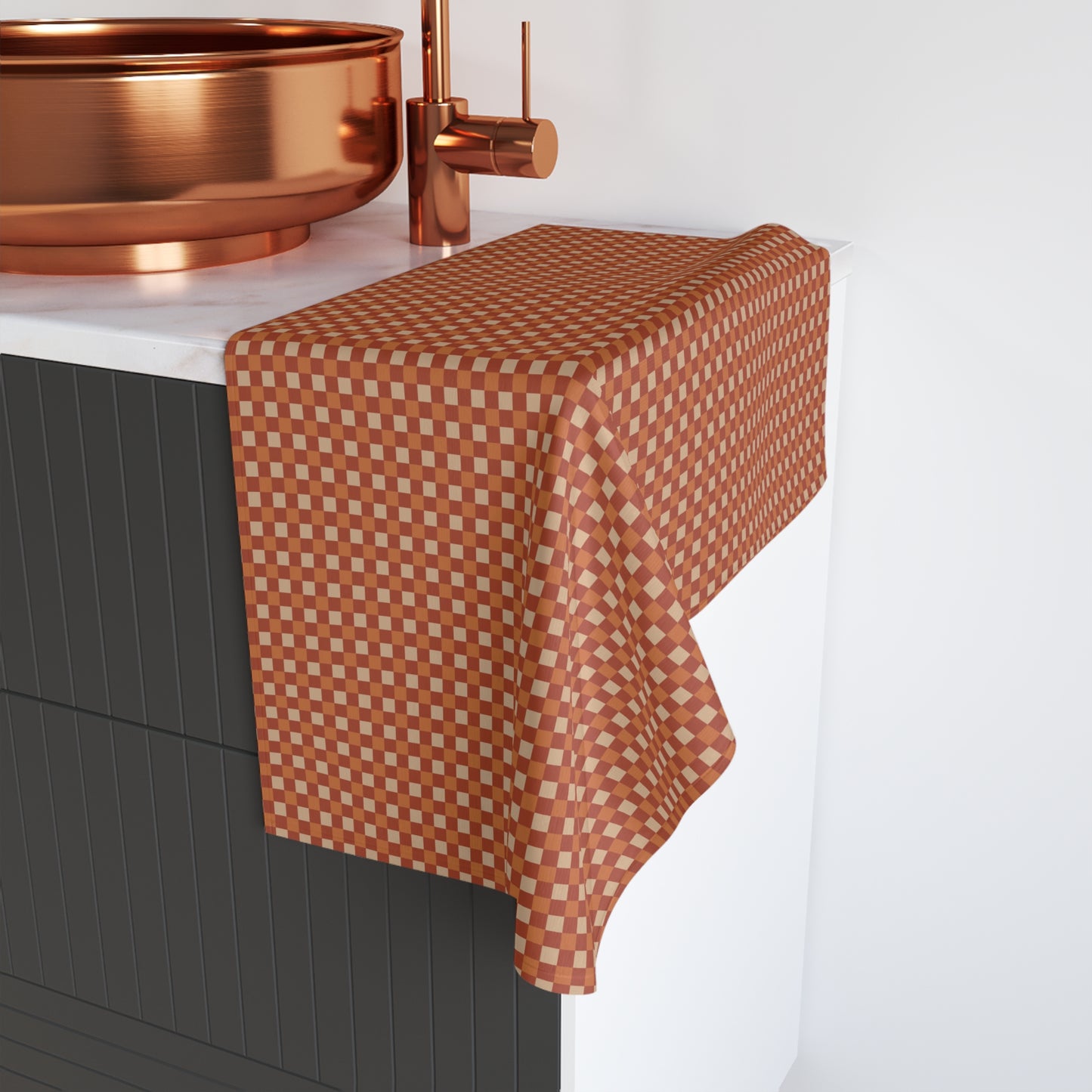 Checkered towel on a black cabinet with copper fixtures