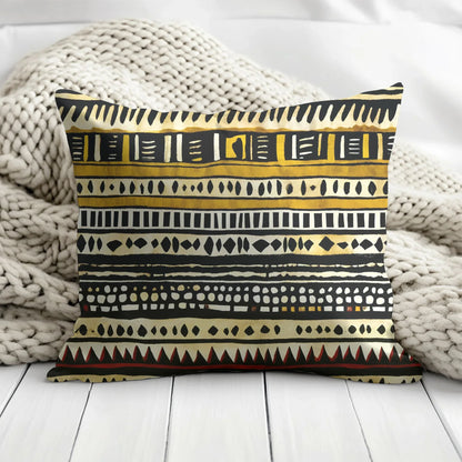 Decorative pillow with black and gold tribal geometric pattern on chunky knit blanket