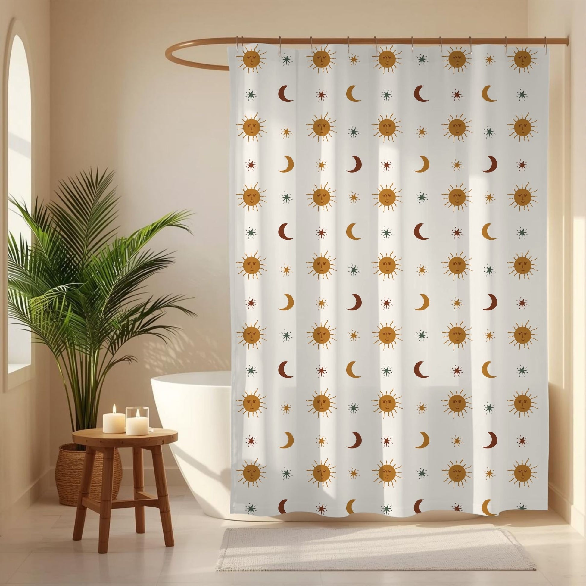 A white shower curtain with a repeating pattern of gold suns, brown crescent moons, and small blue stars, hanging in a bright bathroom next to a potted palm plant and a small wooden stool.