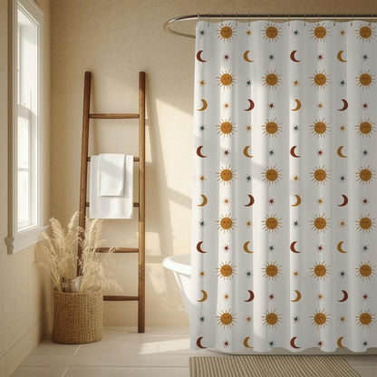 A white shower curtain with a repeating pattern of gold suns, brown and red crescent moons, and small blue stars, hanging in a warm beige bathroom next to a wooden ladder shelf and a window.