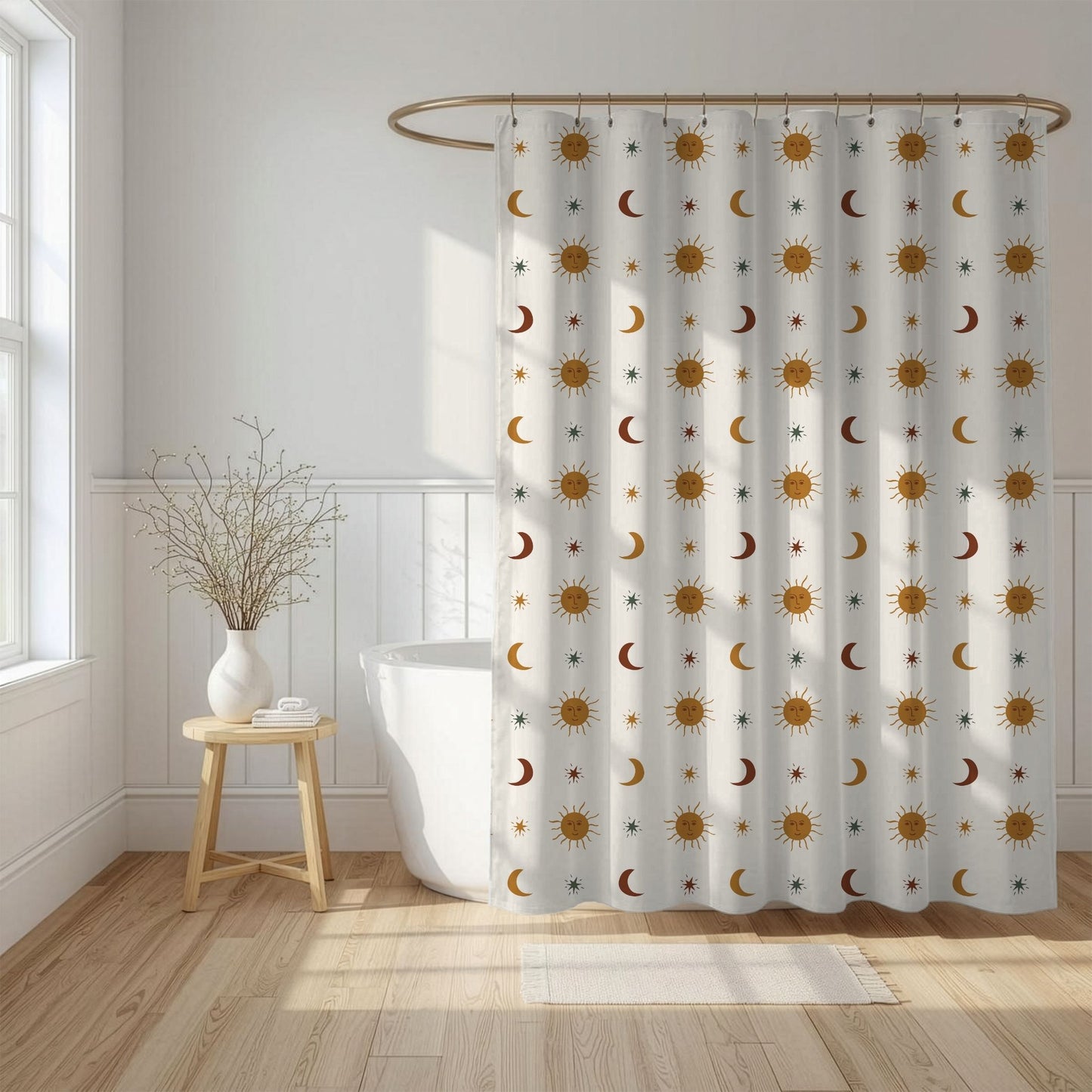A white shower curtain with a repeating pattern of gold and brown suns, crescent moons, and small stars, hanging in a bright, modern bathroom next to a white tub and wooden stool.