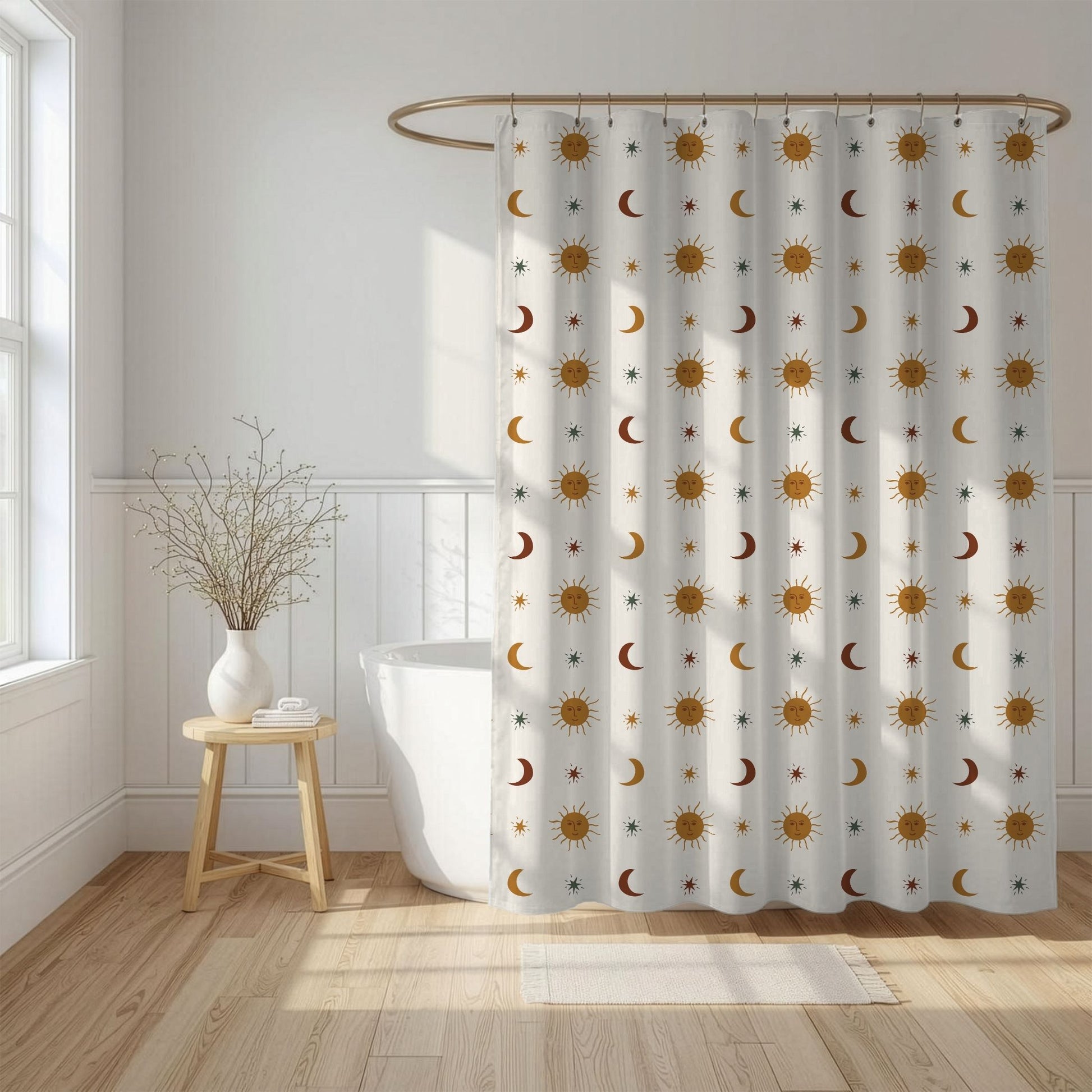 A white shower curtain with a repeating pattern of gold and brown suns, crescent moons, and small stars, hanging in a bright, modern bathroom next to a white tub and wooden stool.