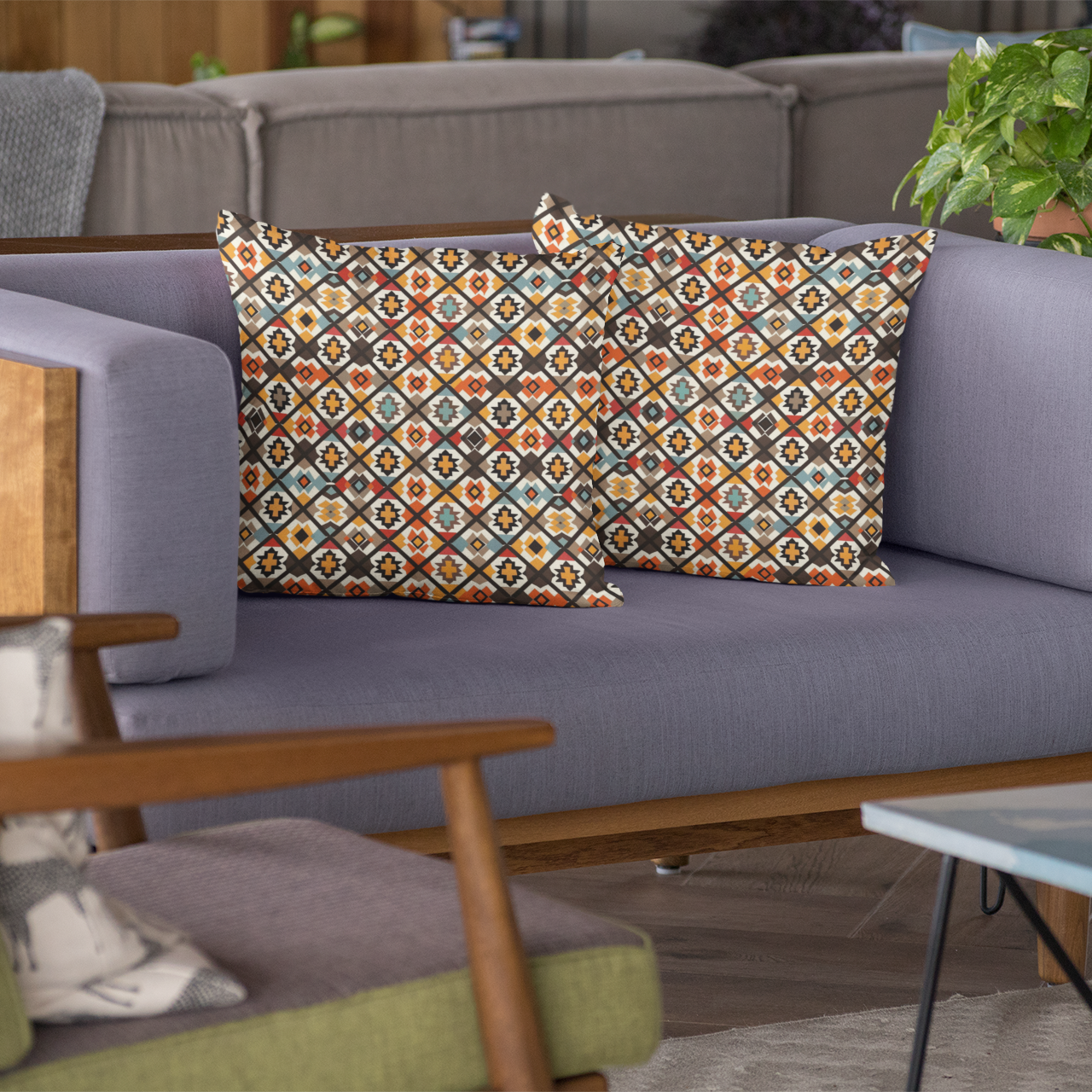 Gray sofa with tribal patterned cushions, green chair, and plant in a living room setting.