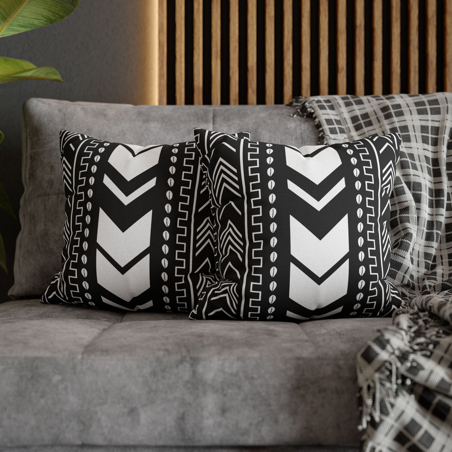Black and white patterned pillows on a gray sofa with a wooden headboard in the background.