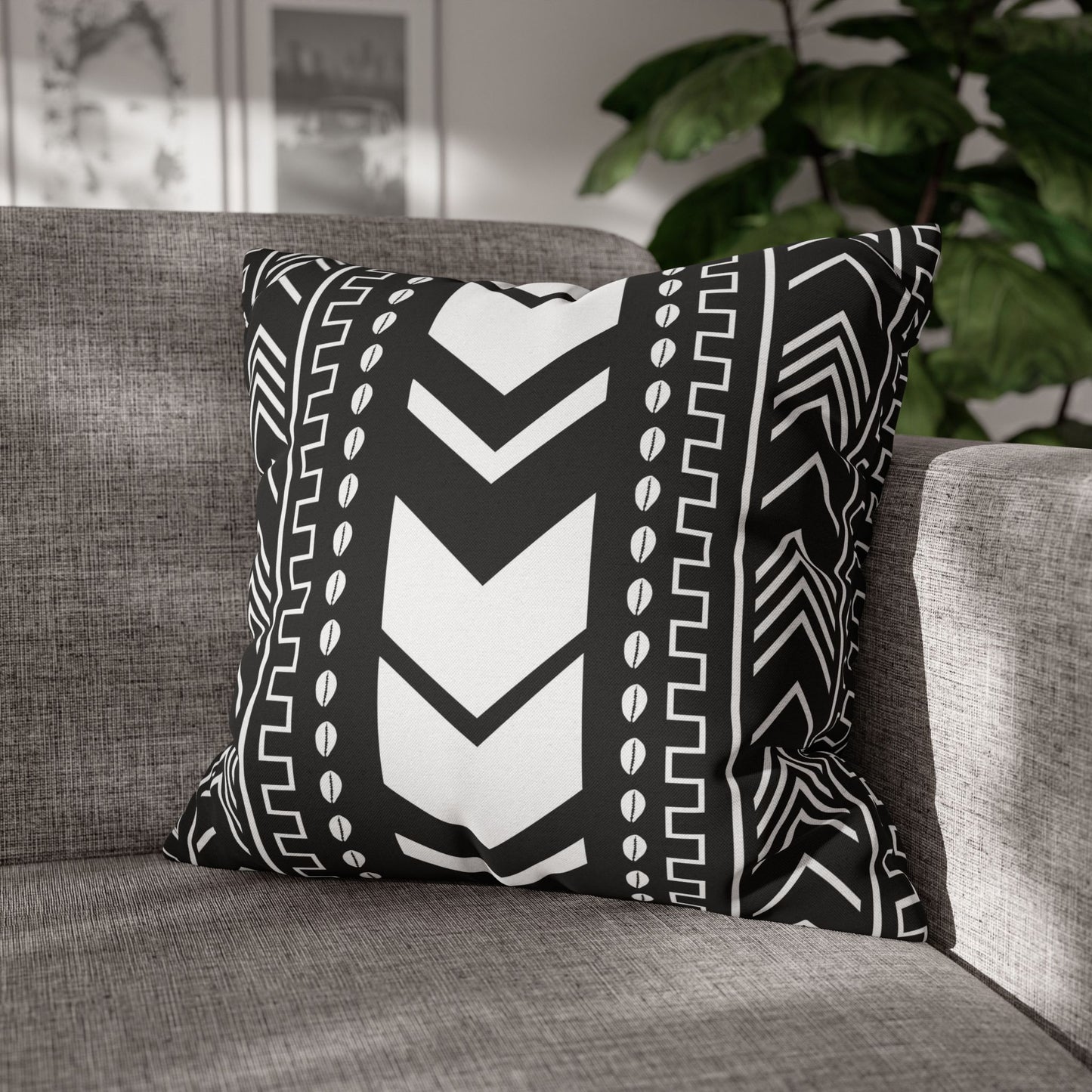 Black and white patterned pillow on a gray sofa with a blurred indoor background