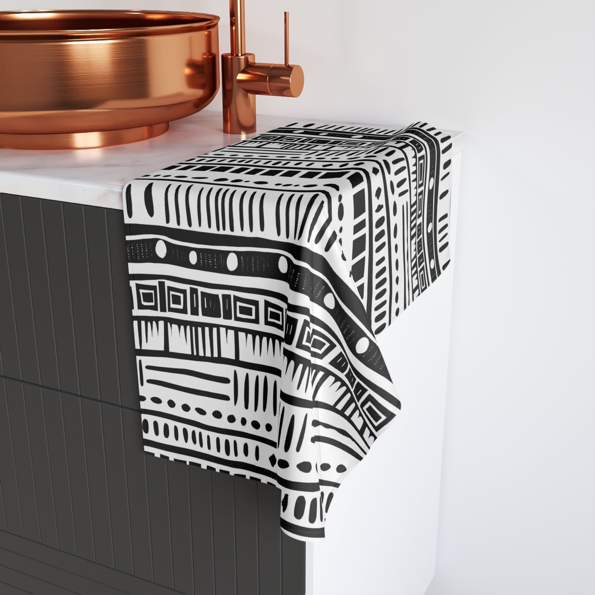Black and white patterned towel draped over a bathroom faucet with copper fixtures.