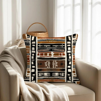 Mudcloth pattern throw pillow on beige armchair with knit blanket in sunlit living room