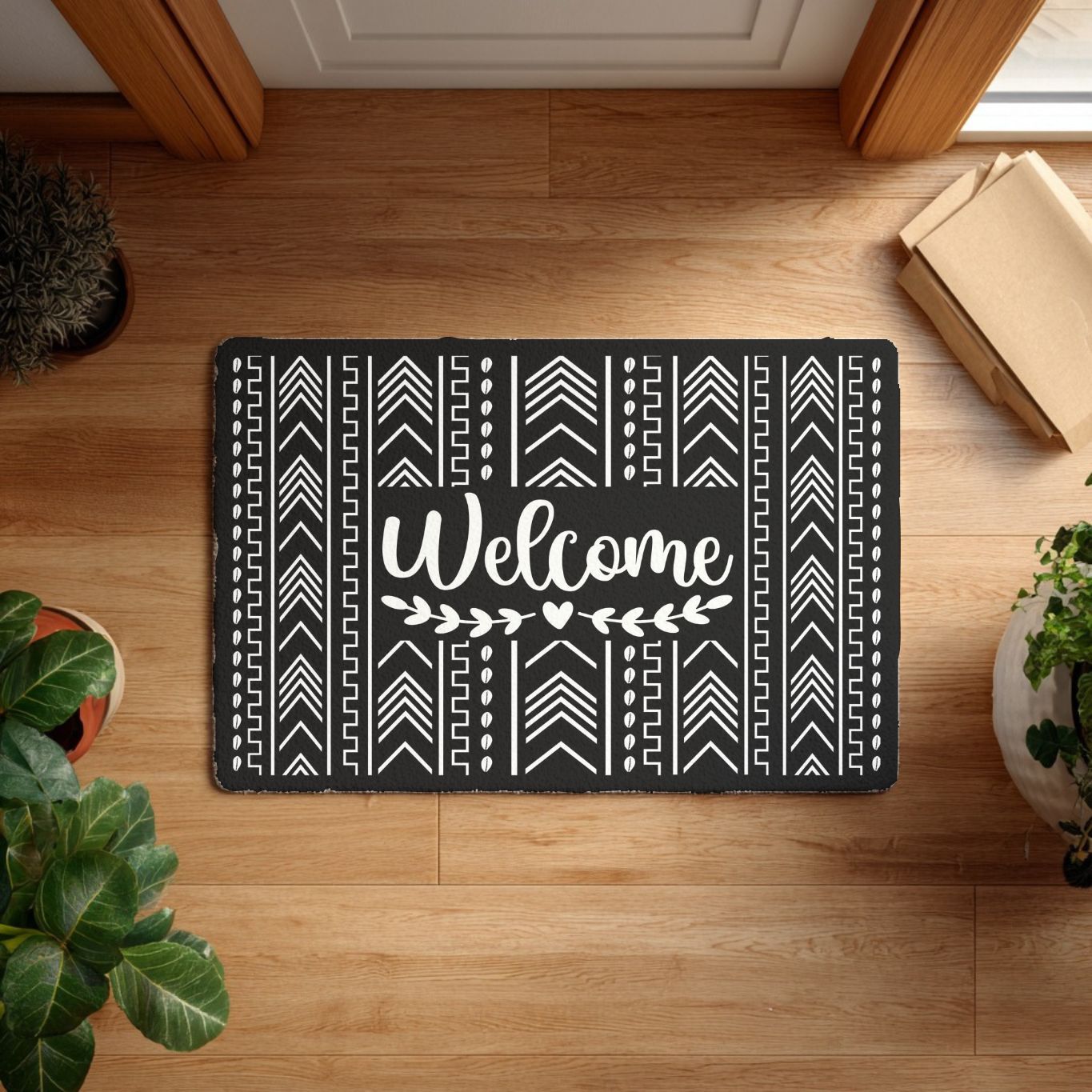 Black doormat with white african shells patterns and 'Welcome' text on a wooden floor.