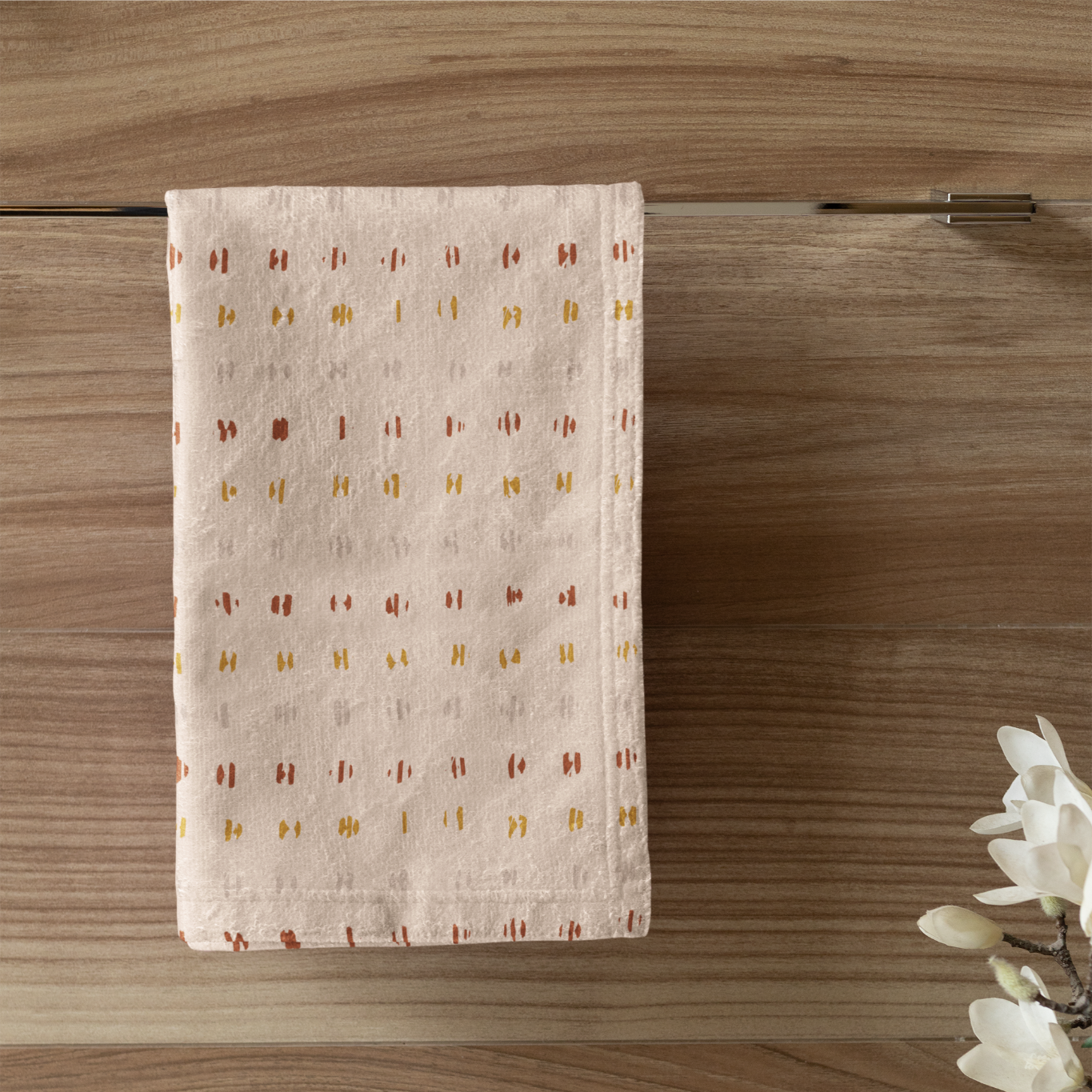 Patterned towel hanging on a wooden wall with a candle and plant in the foreground.