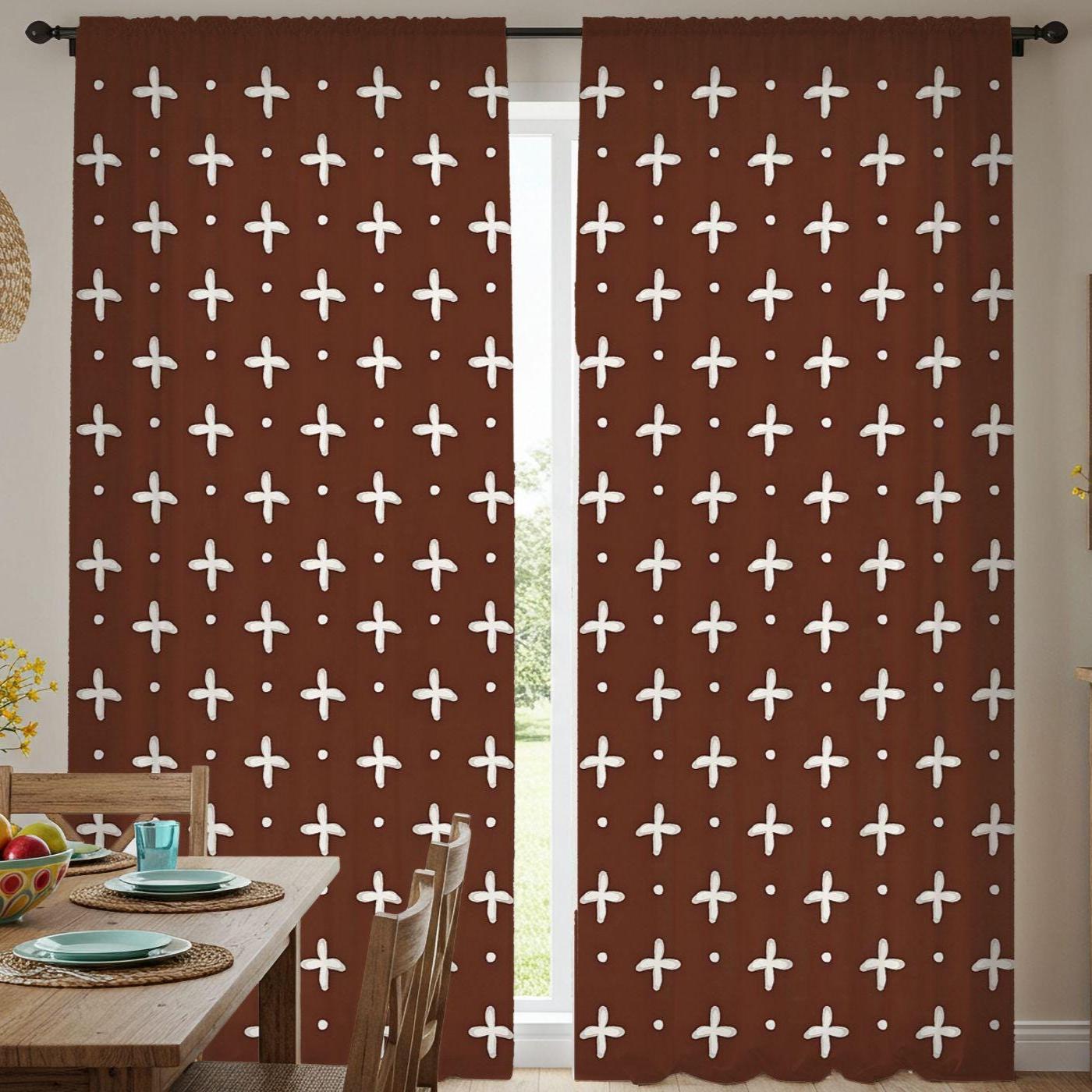 Brown curtains with white cross patterns in a room with a dining table and chairs.