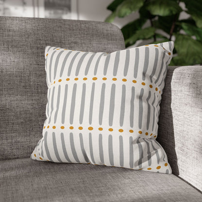 Decorative mudcloth  pillow with gray stripes and yellow dots on a gray sofa.