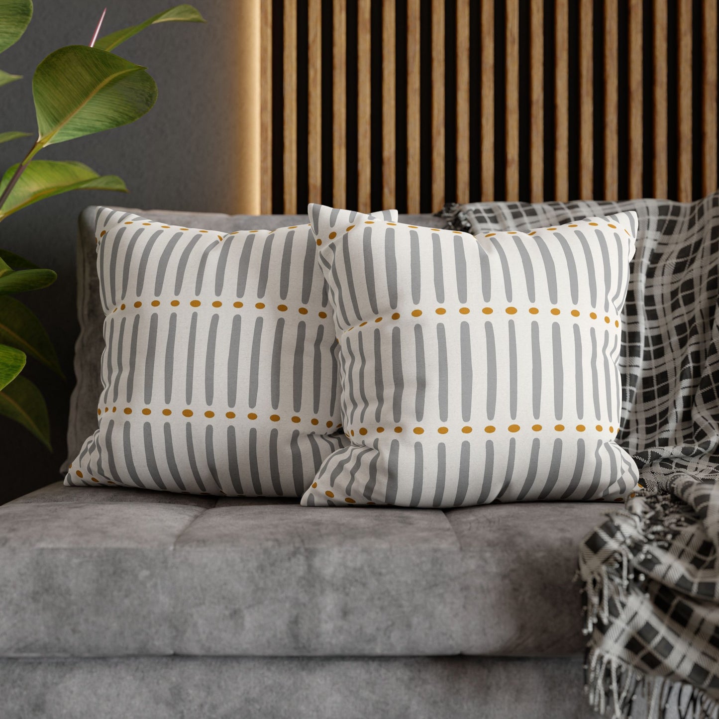 Mudcloth striped pillows with gold accents on a gray sofa.