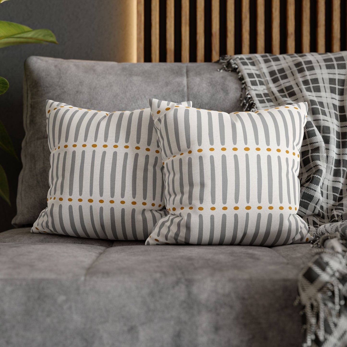 Two patterned cushions on a gray sofa with a wooden headboard in the background.