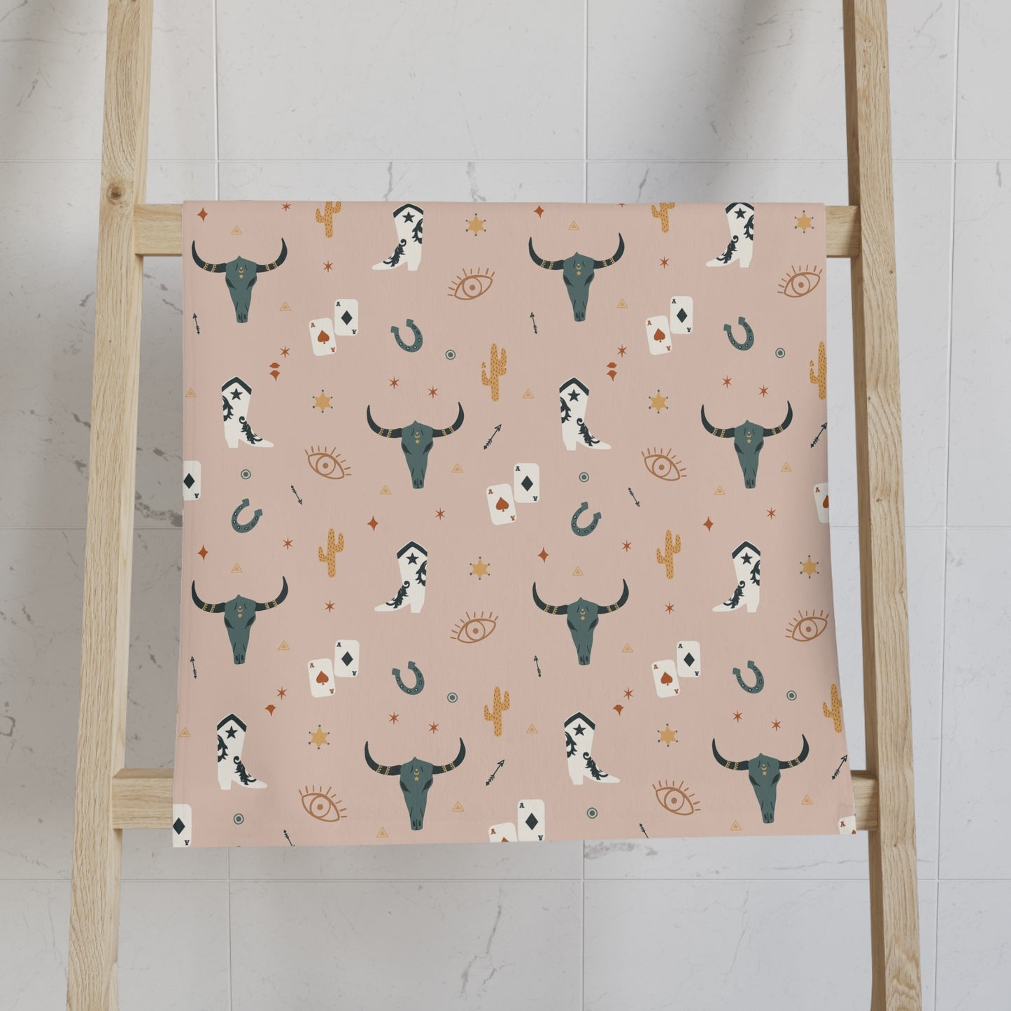 Patterned Hand Towel with a pattern of longhorns, cards, and cacti on a pink background, displayed on a wooden ladder.