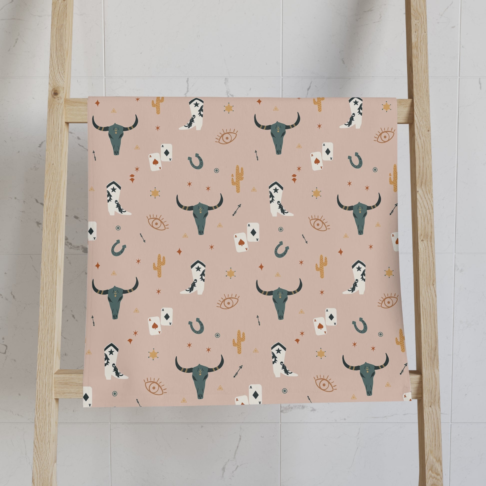 Patterned Hand Towel with a pattern of longhorns, cards, and cacti on a pink background, displayed on a wooden ladder.