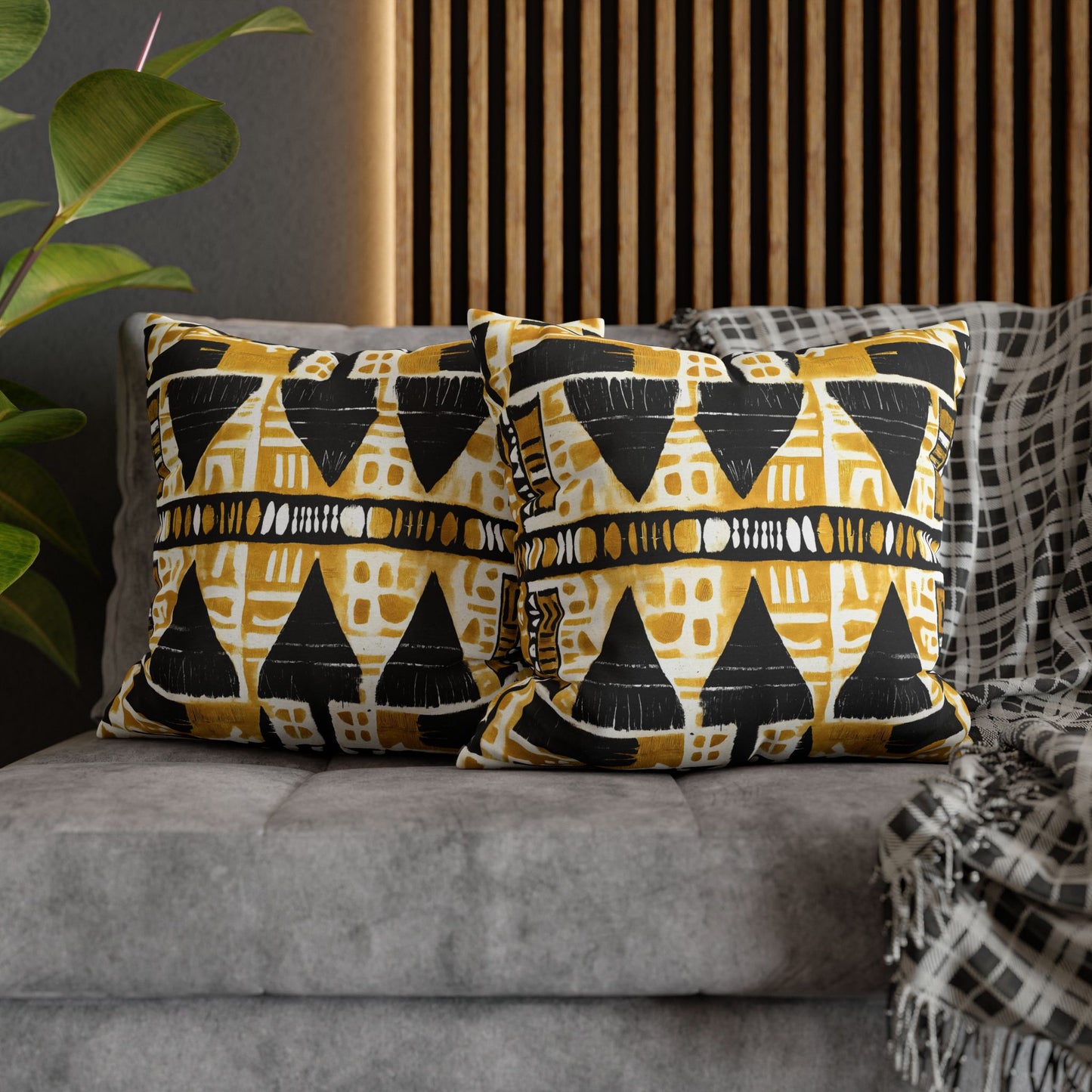 Patterned cushions on a gray sofa with a plant and wooden slat wall in the background