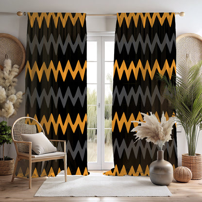 A room with bold black, gold, and gray zigzag mudcloth print blackout curtains hanging on a window, with a chair, a vase with a plant, and a decorative object on the foreground.
