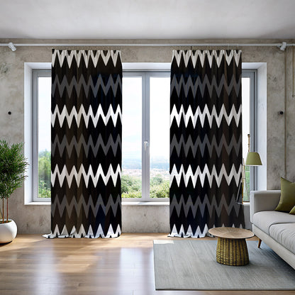 A set of geometric mudcloth print blackout curtains in black, gold, and gray, displayed in a room setting with a window, plants, and furniture.